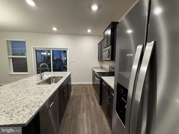 a kitchen with granite countertop cabinets stainless steel appliances and wooden floor