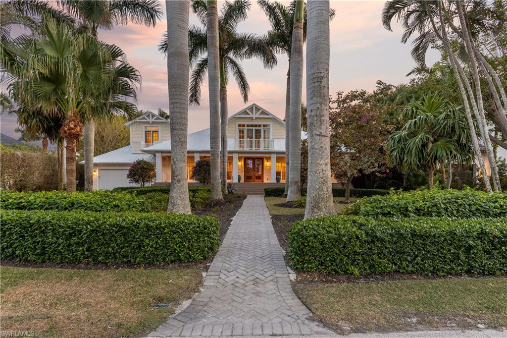front view of a house with a yard and palm trees