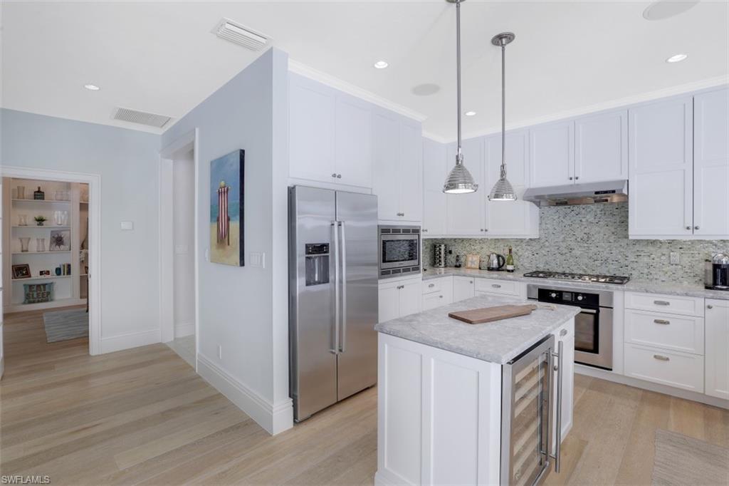 154 4th Avenue North Naples, FL 34102 - Photo 24 of 50 a kitchen with stainless steel appliances granite countertop a stove a sink a refrigerator and white cabinets with wooden floor