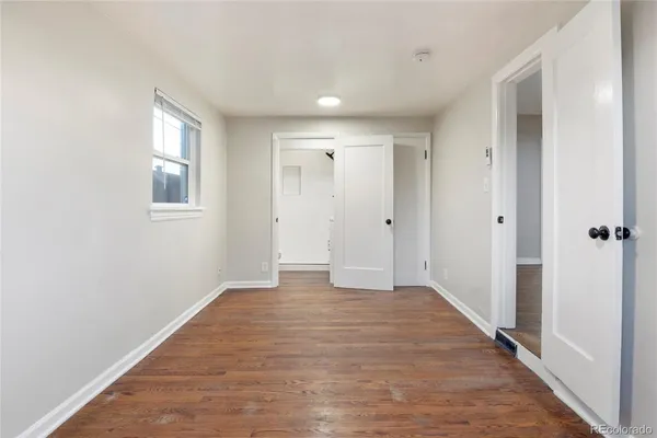 a view of an empty room with wooden floor and a window