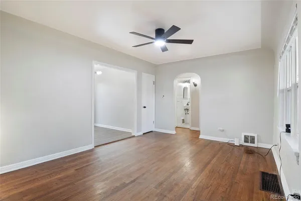 an empty room with wooden floor and ceiling fan