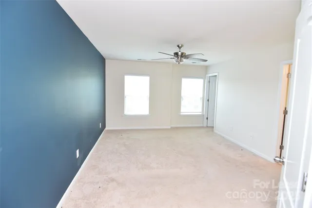 an empty room with windows and chandelier fan