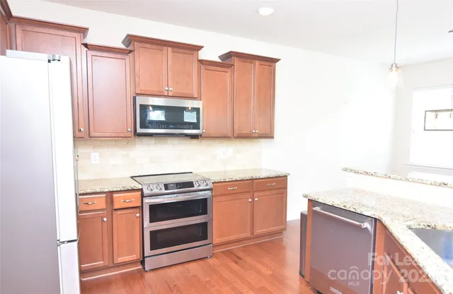 a kitchen with stainless steel appliances granite countertop a stove a microwave and a refrigerator