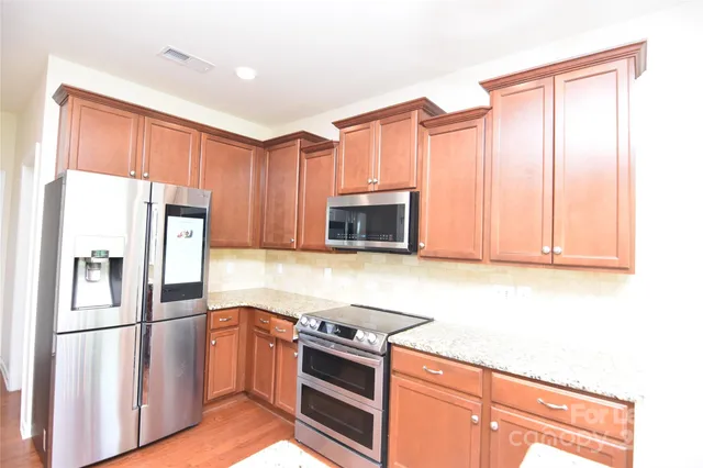 a kitchen with granite countertop a refrigerator stove and microwave
