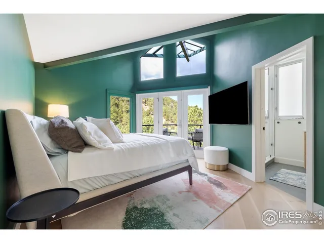 a bedroom with a bed a mirror on the dresser and a large window