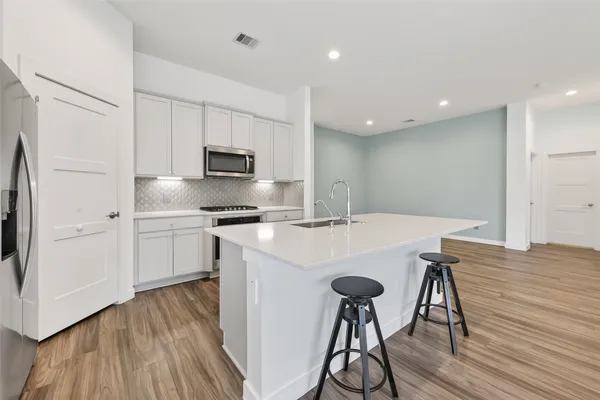 a kitchen with stainless steel appliances a table and chairs in it