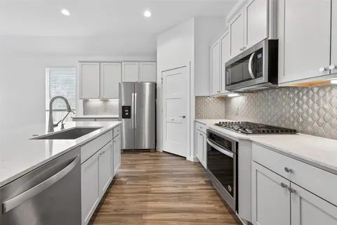 a kitchen with granite countertop cabinets stainless steel appliances and wooden floor