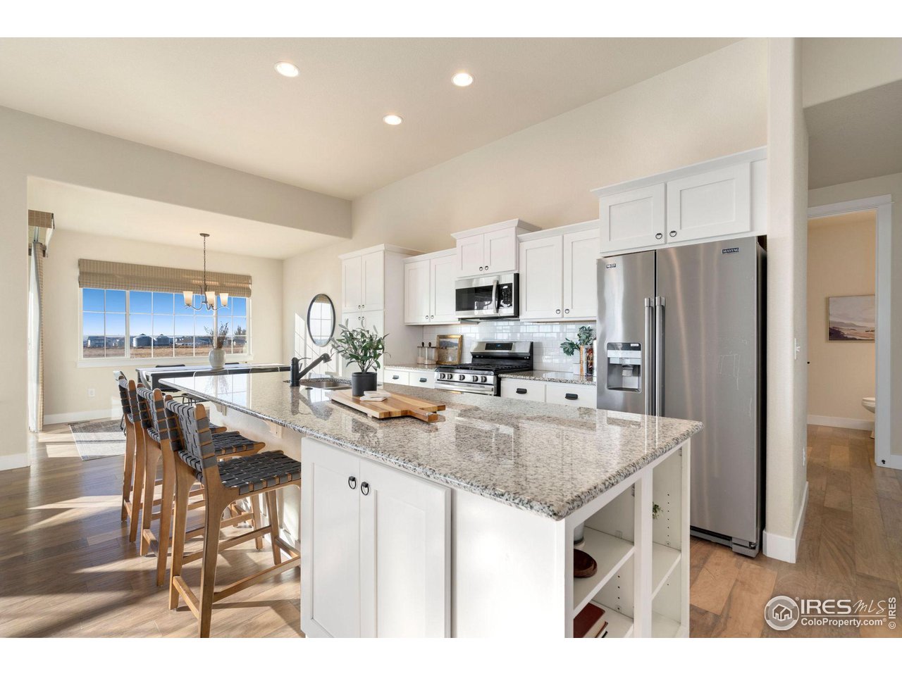 985 Mount Andrew Drive Severance, CO 80550 - Photo 9 of 25 a kitchen with stainless steel appliances granite countertop a table chairs sink refrigerator and microwave