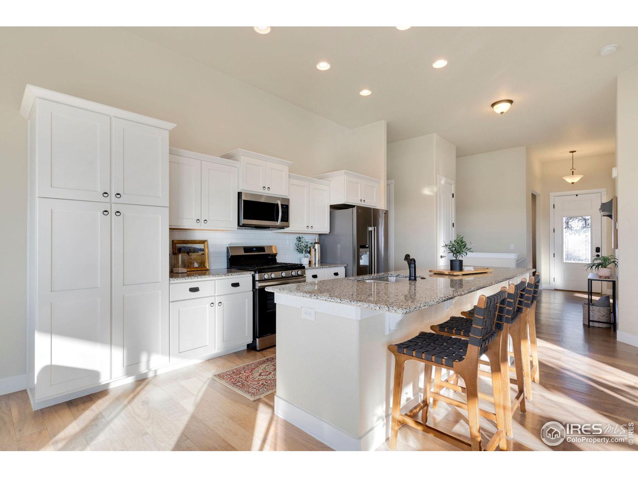 985 Mount Andrew Drive Severance, CO 80550 - Photo 10 of 25 a kitchen with stainless steel appliances kitchen island granite countertop a refrigerator a stove a sink a microwave oven with a dining table and chairs