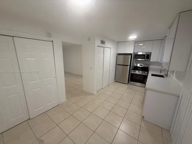 a kitchen with a refrigerator and white cabinets