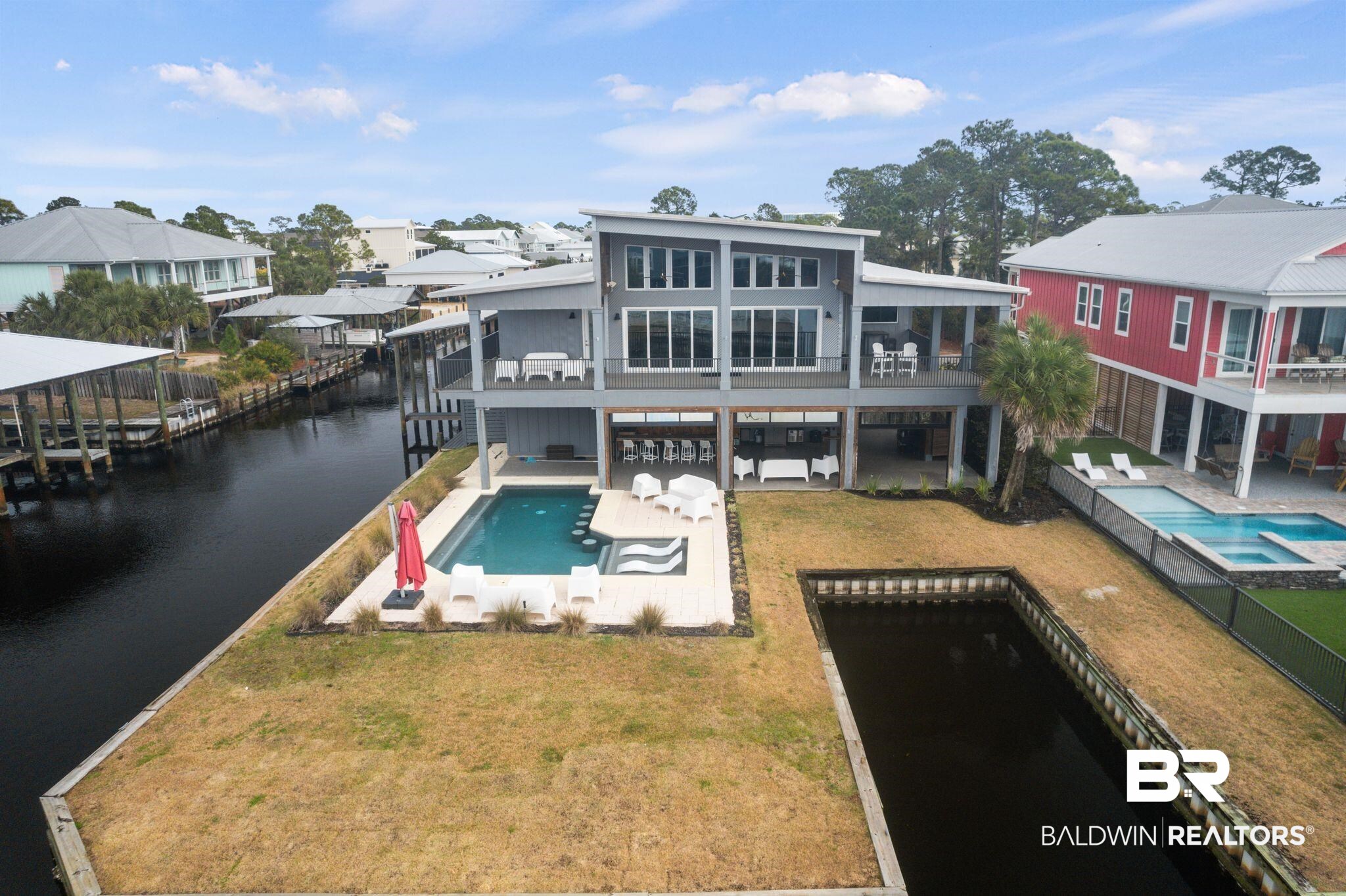 3840 Cotton Way Orange Beach, AL 36561 - Photo 1 of 75 Rear view of property with a balcony, a pool with hot tub, a water view, a patio area, and a lawn