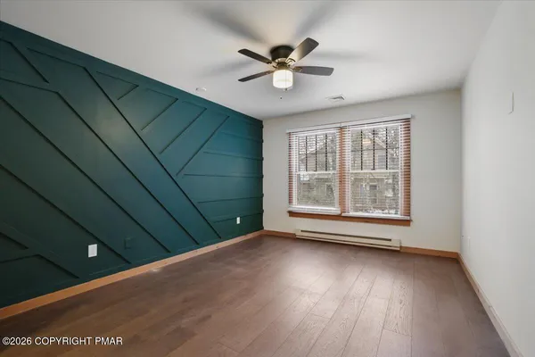 a view of an empty room with a window and wooden floor