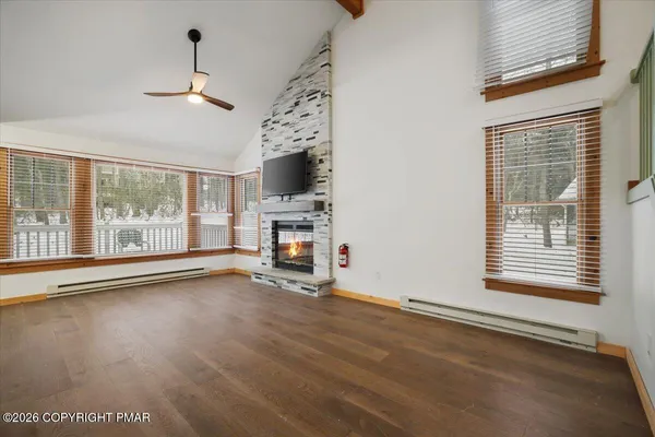 a view of an empty room with a window and wooden floor