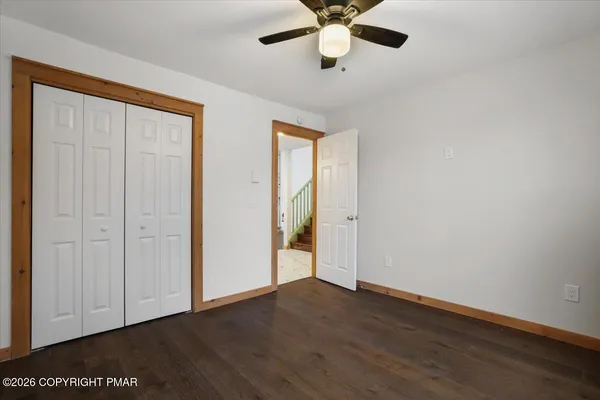 an empty room with wooden floor closet and windows