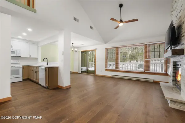 a view of a kitchen with furniture a ceiling fan and wooden floor