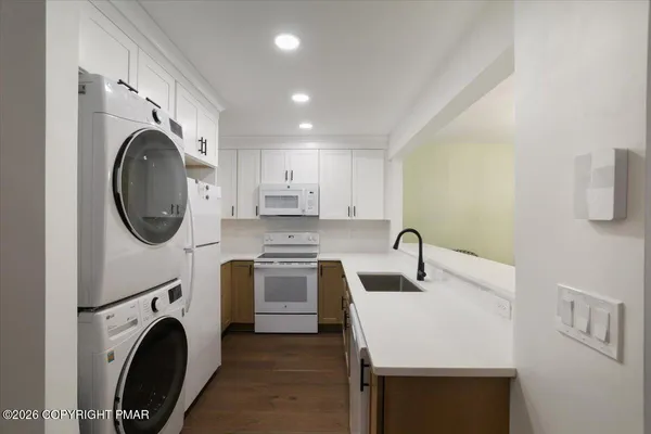 a kitchen with stainless steel appliances granite countertop a sink a stove a washer and dryer