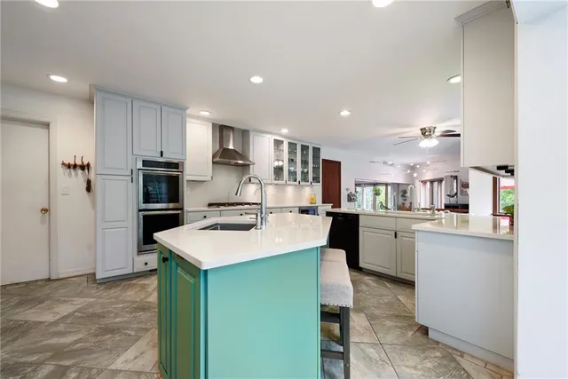a room with kitchen island a sink a stove a refrigerator and a cabinets
