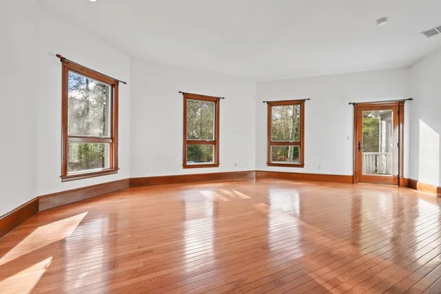 a view of an empty room with window and wooden floor