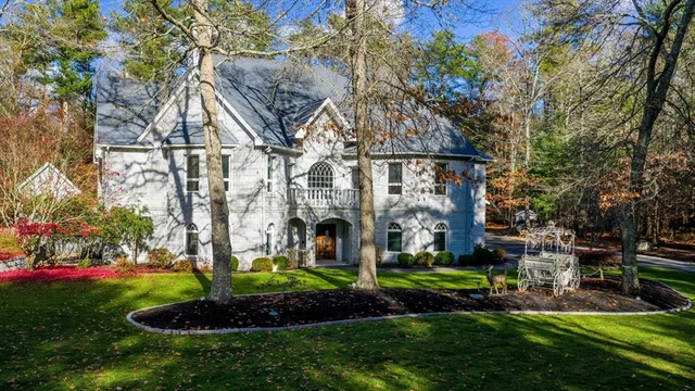 a view of a white house next to a yard and a large tree