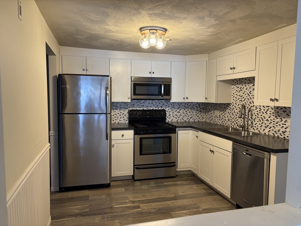a kitchen with granite countertop a refrigerator stove and sink