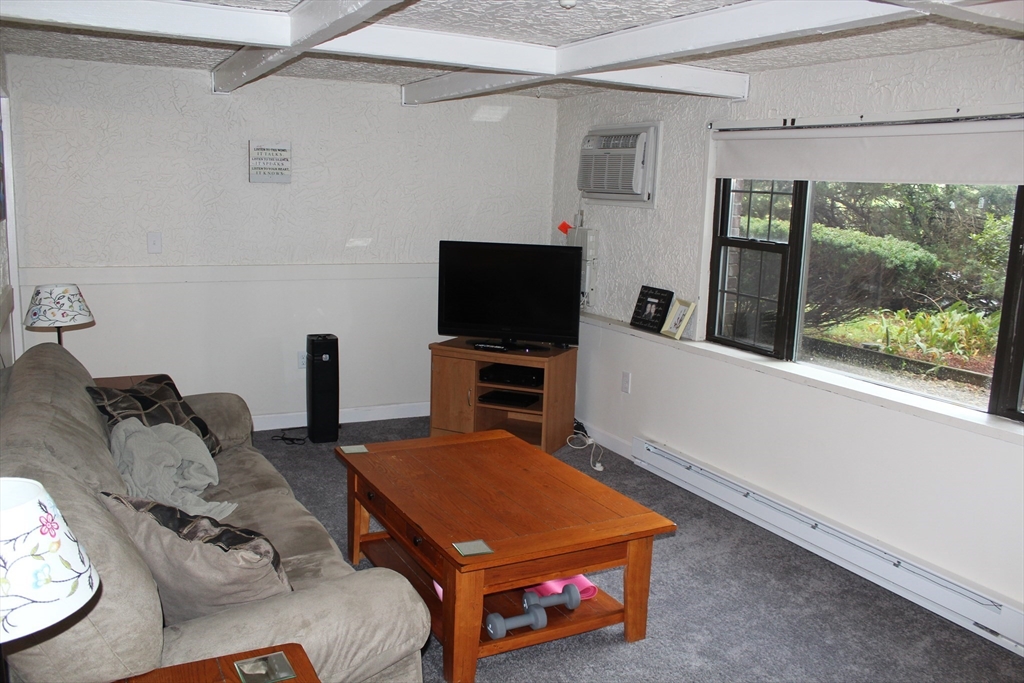 24 Spencer Road, Unit 12N Boxborough, MA 01719 - Photo 2 of 7 a living room with furniture a flat screen tv and a floor to ceiling window