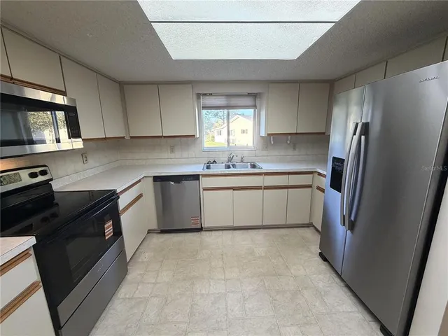 a view of a refrigerator in kitchen and an empty room