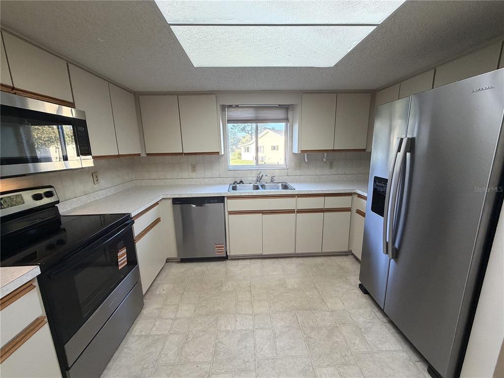 10980 Southwest 62nd Avenue Ocala, FL 34476 - Photo 11 of 48 a kitchen with a sink a refrigerator and cabinets