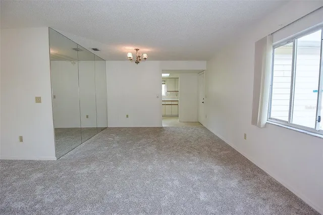 an empty room with chandelier fan and windows