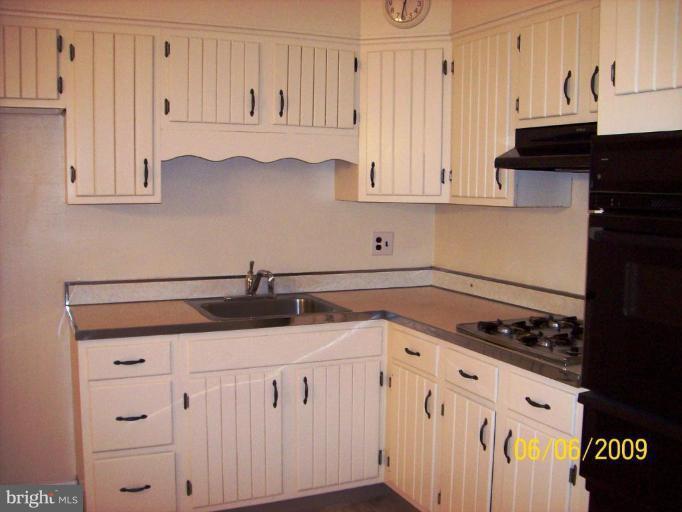 8208 Edwill Avenue Rosedale, MD 21237 - Photo 10 of 18 a kitchen with granite countertop white cabinets and black appliances