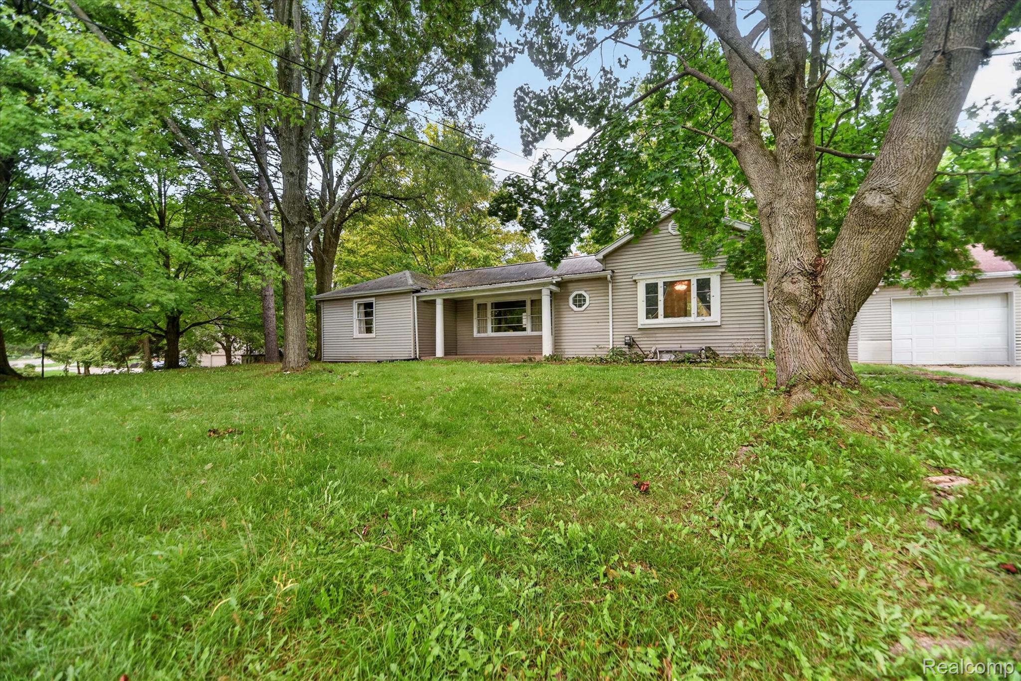1730 Haslett Road Haslett, MI 48840 - Photo 4 of 31 Ranch-style residence featuring a prominent front lawn, mature trees, an attached garage, and a bay window