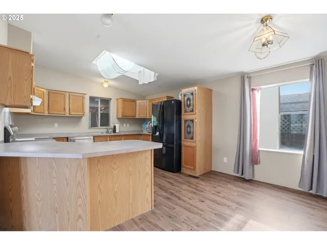 a kitchen with stainless steel appliances granite countertop a refrigerator a sink dishwasher and a stove with wooden floor