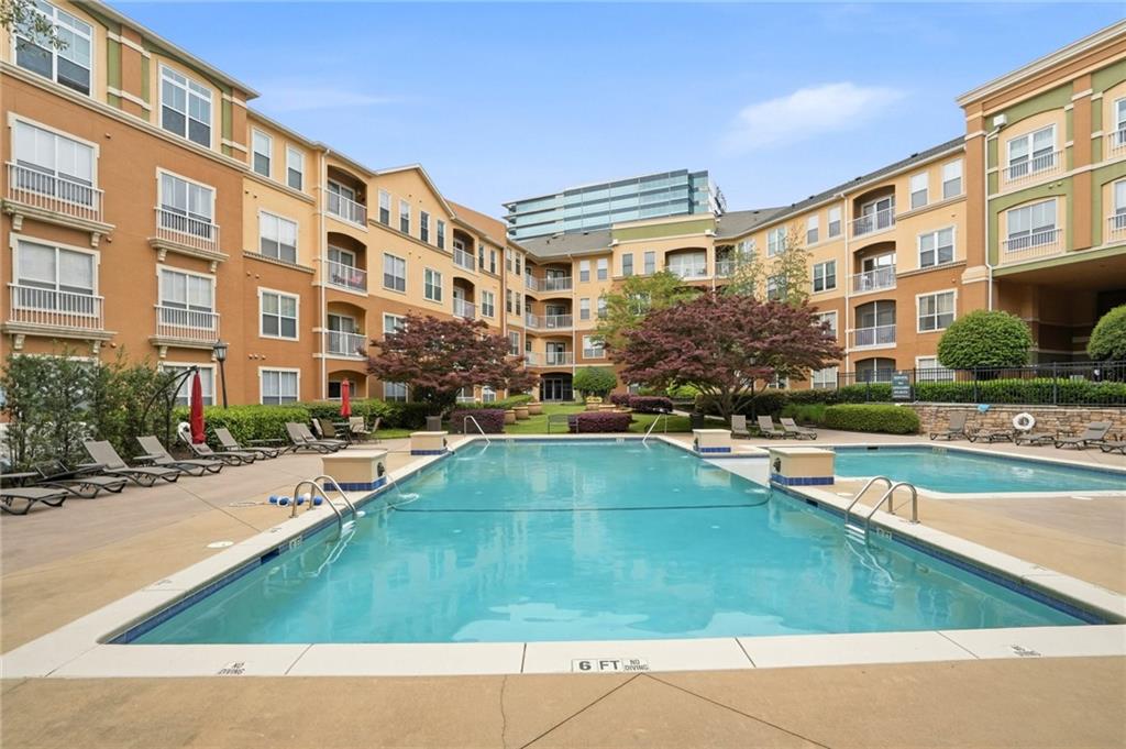 10 Perimeter Summit Boulevard, Unit 1204 Atlanta, GA 30319 - Photo 12 of 39 a view of a swimming pool with a lounge chairs in front of a building