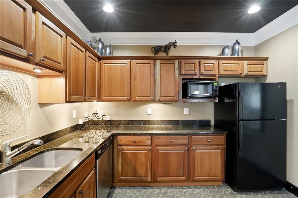 10 Perimeter Summit Boulevard, Unit 1204 Atlanta, GA 30319 - Photo 20 of 39 a kitchen with stainless steel appliances granite countertop a refrigerator a stove and a sink with wooden cabinets
