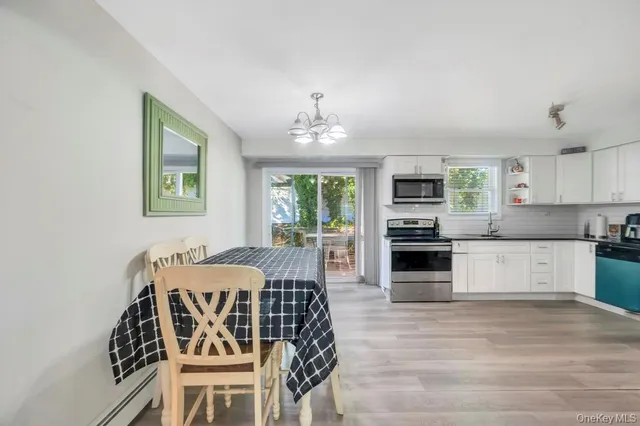 a open kitchen with granite countertop a stove top oven a sink dishwasher a dining table and chairs with wooden floor