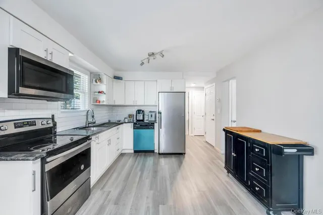 a kitchen with stainless steel appliances a stove a sink dishwasher a refrigerator and a stove with wooden floor