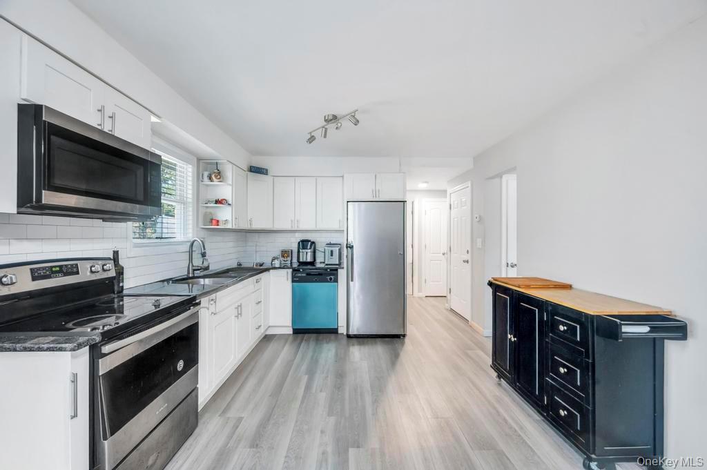 382 Boyle Road Selden, NY 11784 - Photo 15 of 26 a kitchen with stainless steel appliances a stove a sink dishwasher a refrigerator and a stove with wooden floor