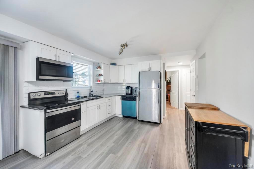 382 Boyle Road Selden, NY 11784 - Photo 16 of 26 a kitchen with stainless steel appliances a refrigerator a stove top oven a sink dishwasher and wooden floor