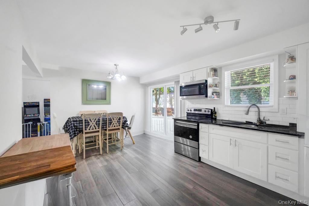 382 Boyle Road Selden, NY 11784 - Photo 17 of 26 a kitchen with stainless steel appliances granite countertop a stove top oven a sink a dining table and chairs with wooden floor