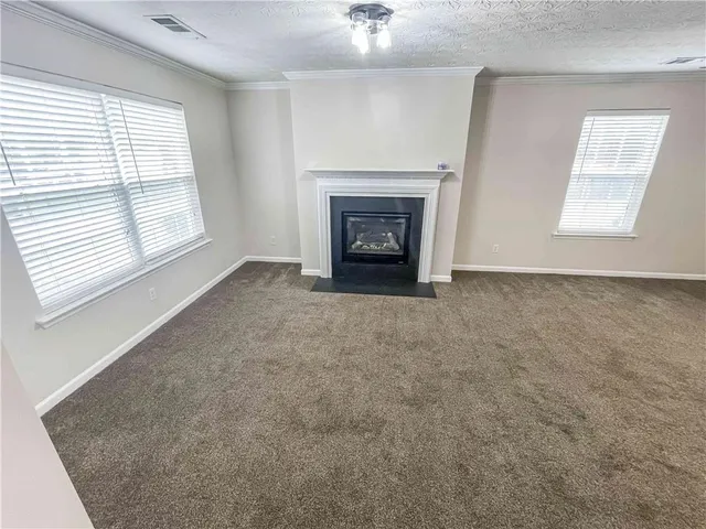 an empty room with windows and fireplace