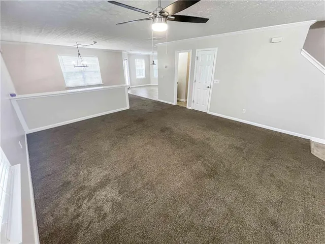 en empty room with windows and ceiling fan