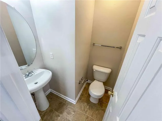 a white toilet sitting next to a bathroom sink and a mirror