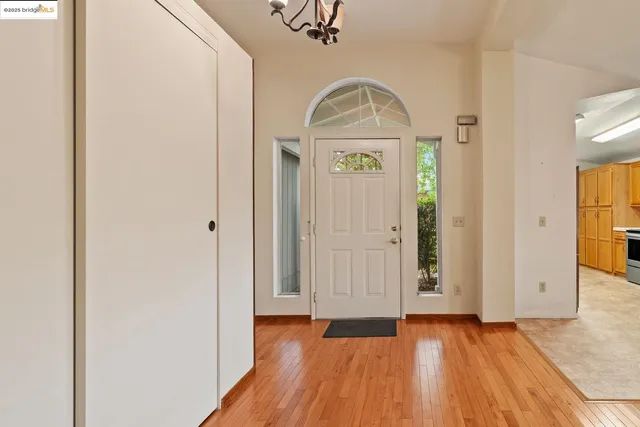 an empty room with wooden floor mirror and windows