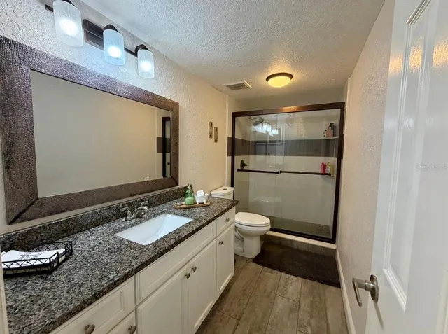 a bathroom with a granite countertop sink toilet and mirror