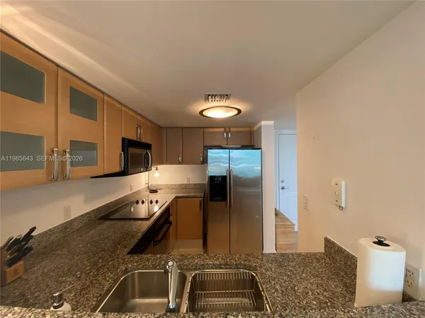 a kitchen with stainless steel appliances granite countertop a sink and a refrigerator