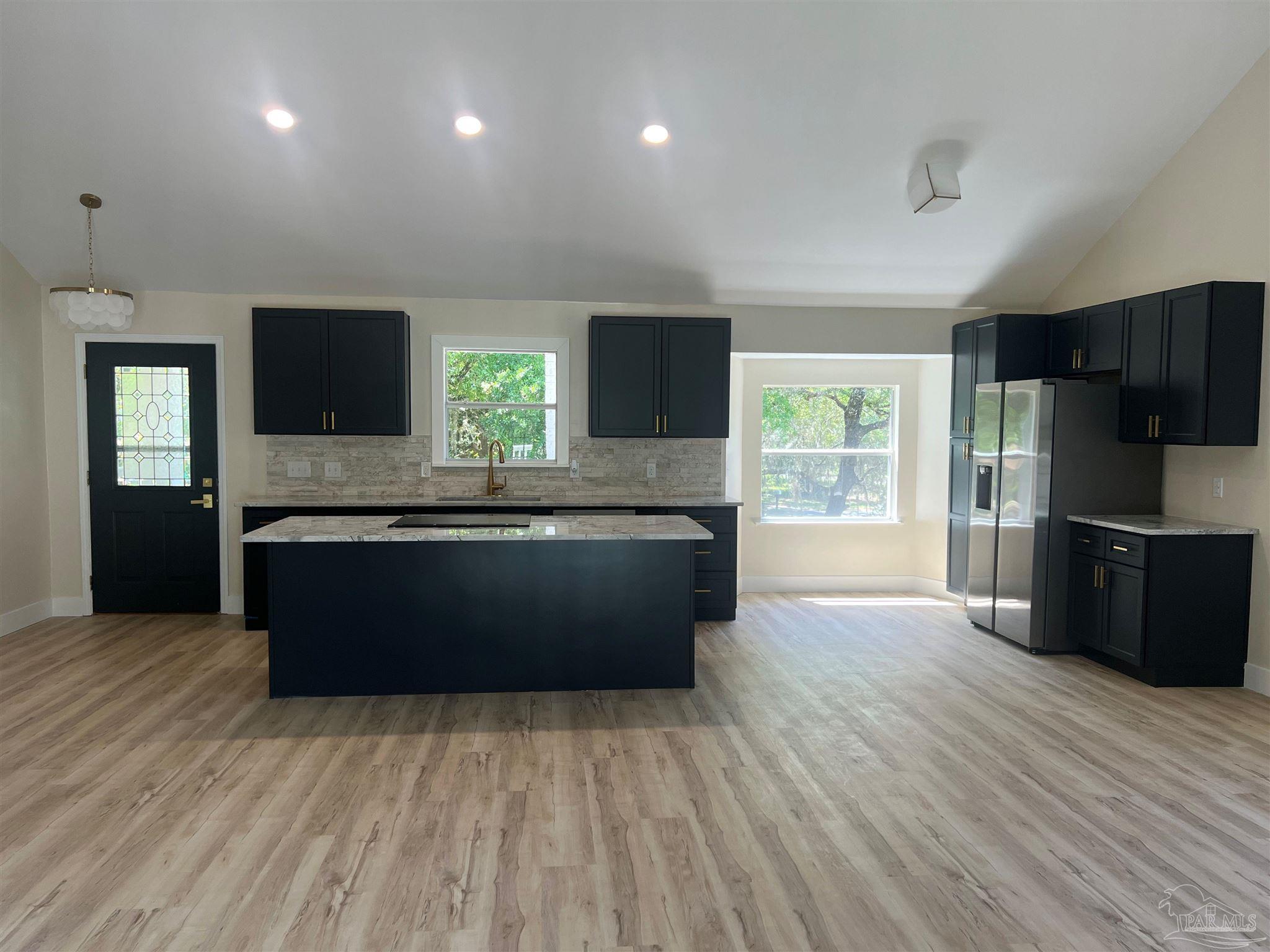 3111 Holley Point Road Navarre, FL 32566 - Photo 5 of 23 a large kitchen with granite countertop a large counter top stainless steel appliances and wooden floor