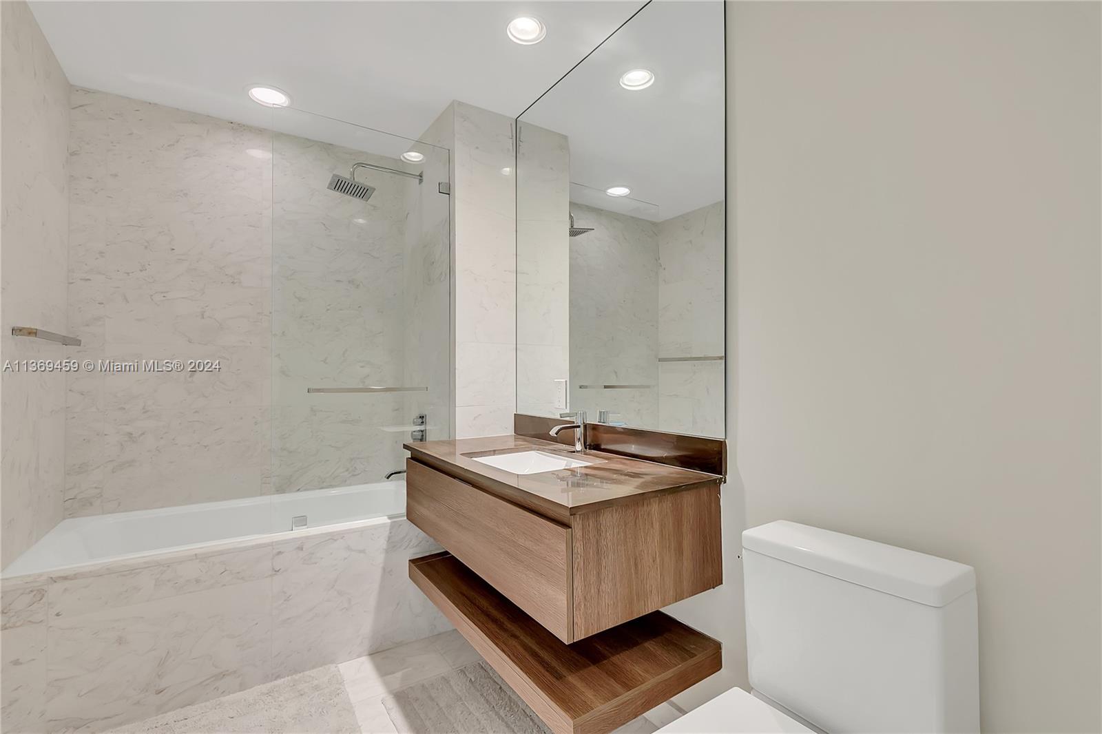 360 Ocean Drive, Unit 205S Key Biscayne, FL 33149 - Photo 16 of 27 a bathroom with a granite countertop sink a toilet a mirror and bathtub