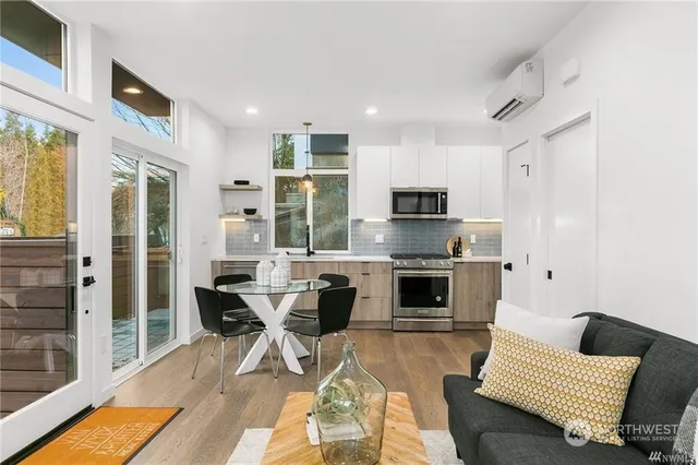 a living room with stainless steel appliances furniture a fireplace and a open kitchen view