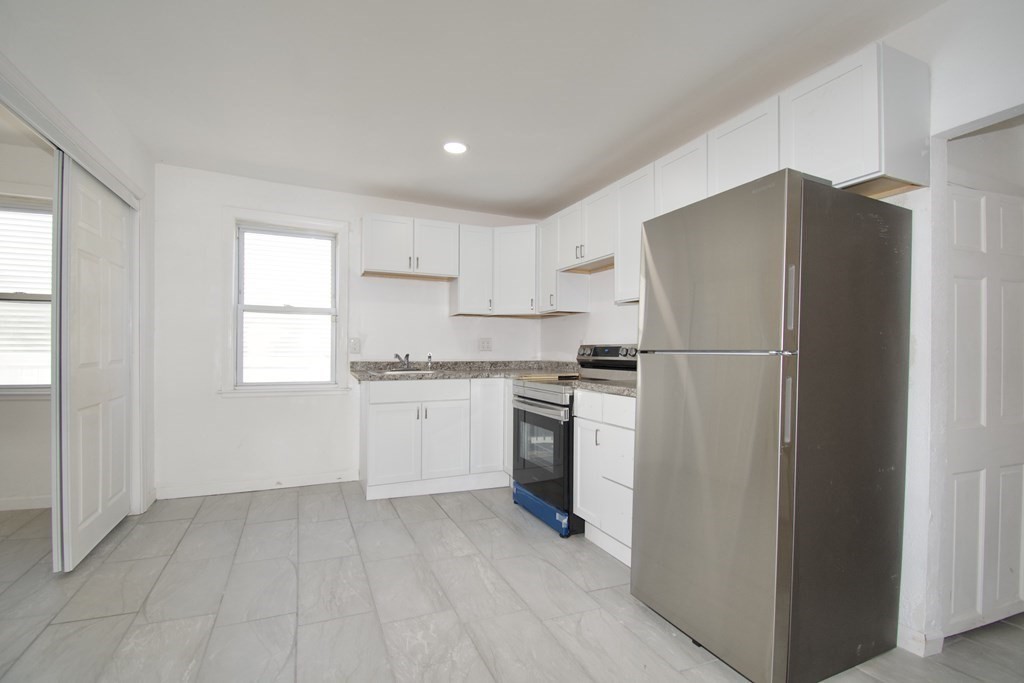 79 Quincy Street Springfield, MA 01109 - Photo 4 of 27 a kitchen with a refrigerator and white cabinets