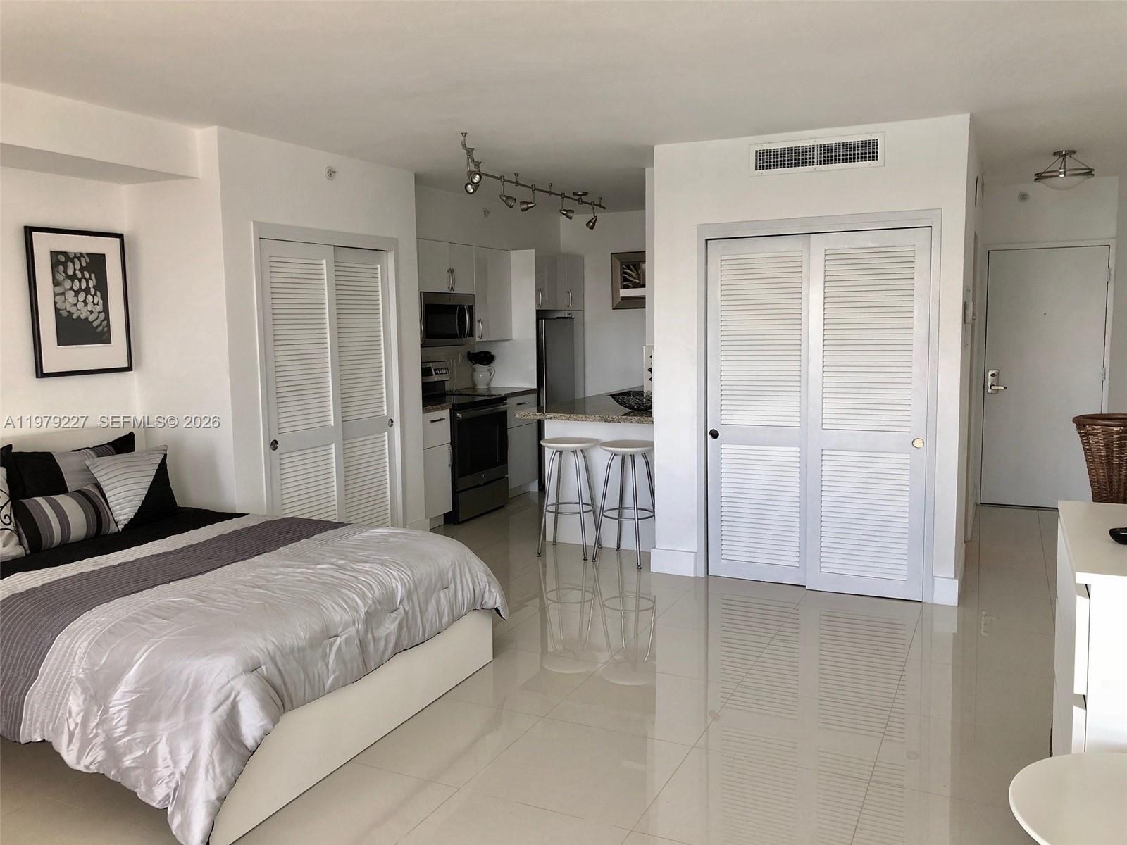 1500 Bay Road, Unit 1236S Miami Beach, FL 33139 - Photo 6 of 24 a spacious bedroom with a bed and a refrigerator