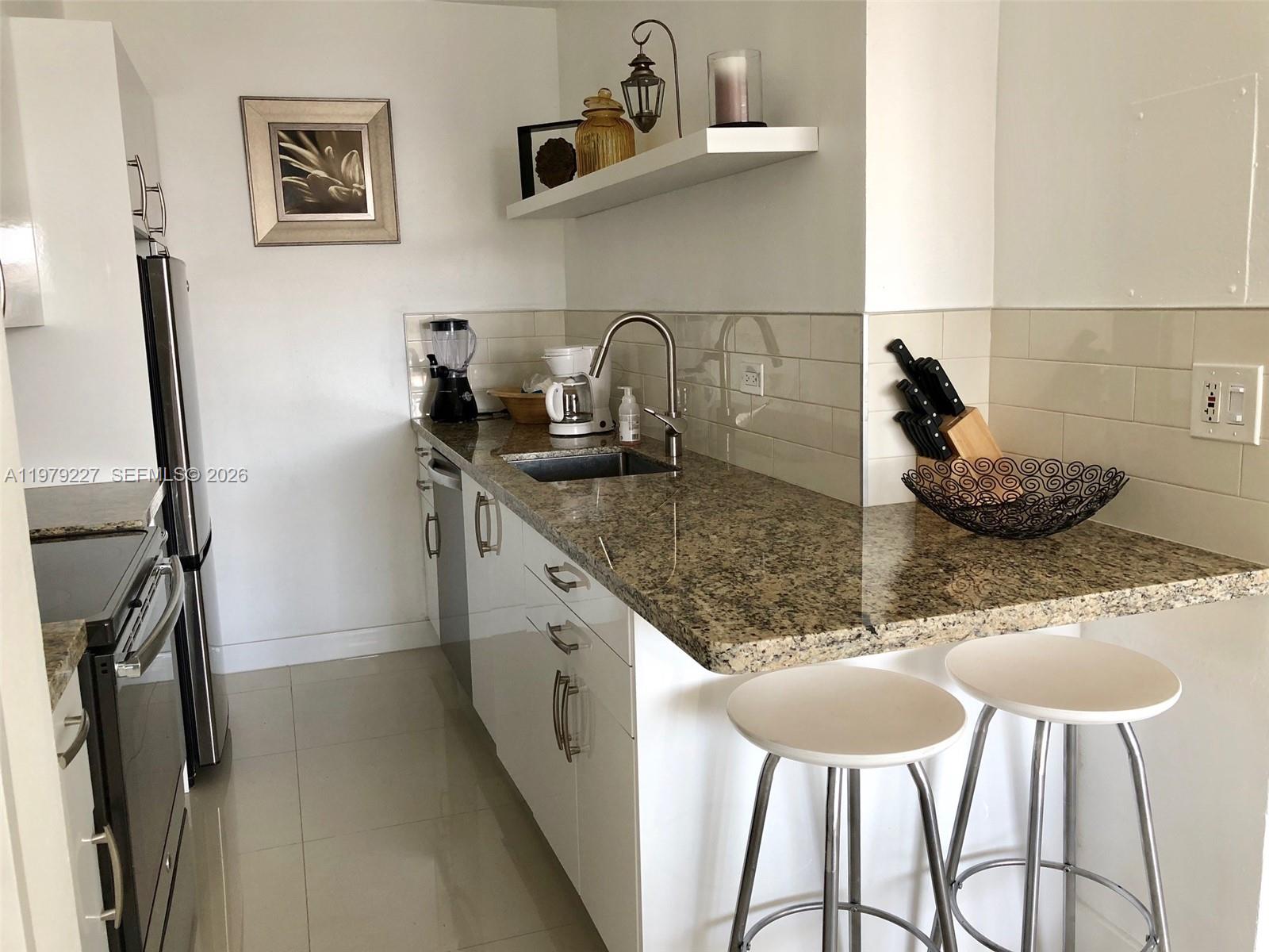 1500 Bay Road, Unit 1236S Miami Beach, FL 33139 - Photo 8 of 24 a kitchen with stainless steel appliances granite countertop a sink and a refrigerator